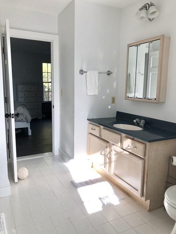 ensuite bathroom featuring tile patterned flooring, vanity, connected bathroom, and toilet