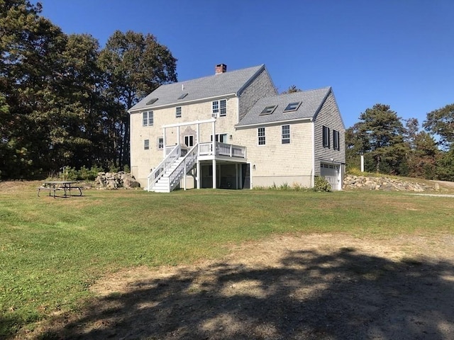 back of property featuring a yard, stairs, a chimney, a garage, and a deck