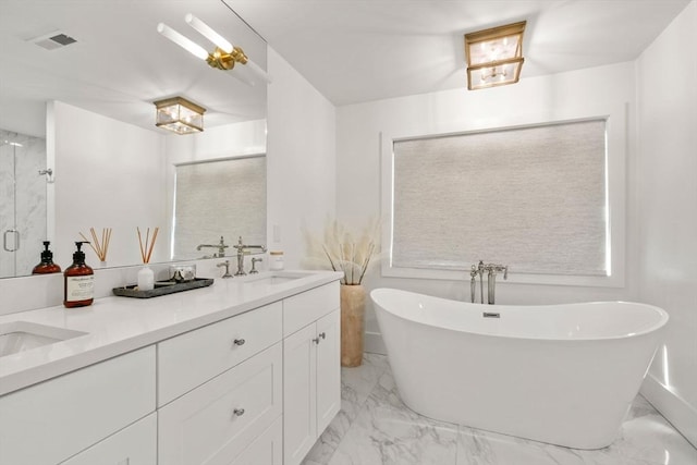 bathroom with double vanity, a freestanding tub, a sink, and marble finish floor