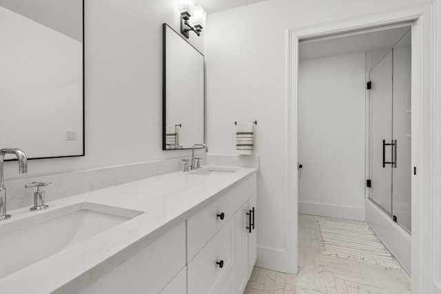 bathroom featuring double vanity, a sink, baseboards, and bath / shower combo with glass door