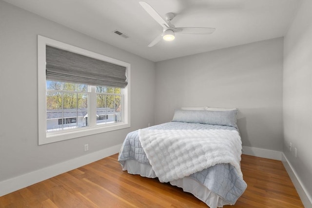 bedroom with visible vents, baseboards, ceiling fan, and wood finished floors