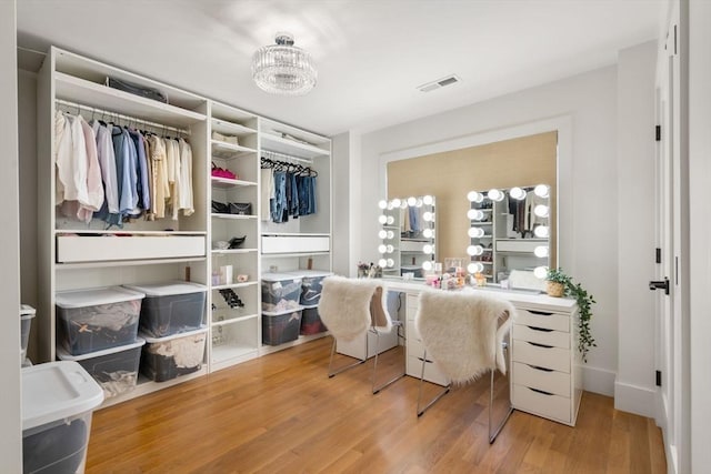 spacious closet featuring visible vents, wood finished floors, and a chandelier