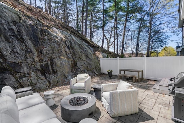 view of patio with grilling area, fence, and an outdoor living space with a fire pit