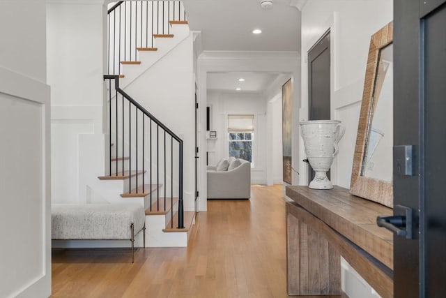 foyer entrance featuring crown molding, recessed lighting, stairs, and wood finished floors