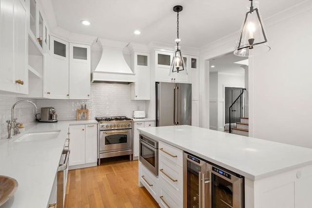 kitchen with a sink, high end appliances, custom exhaust hood, and beverage cooler