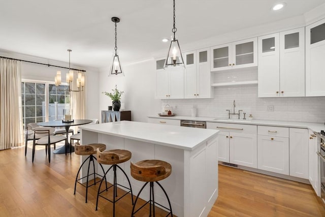 kitchen featuring a kitchen breakfast bar, a center island, tasteful backsplash, a sink, and light wood finished floors