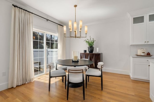 dining room with baseboards, light wood-style flooring, and a notable chandelier