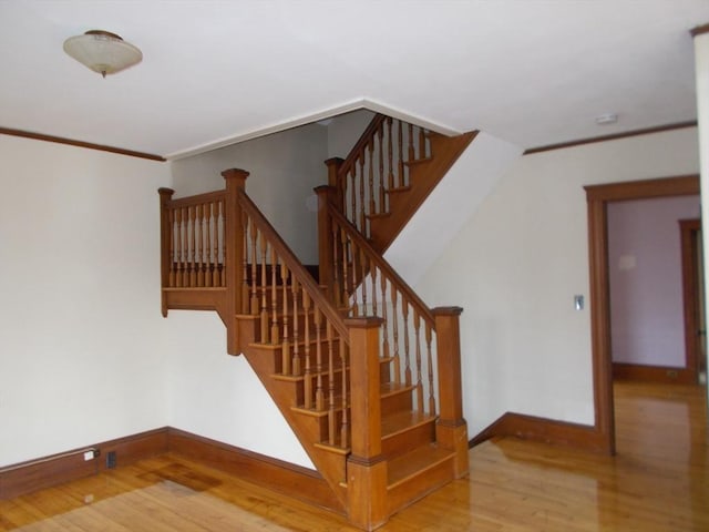 staircase featuring crown molding and hardwood / wood-style flooring