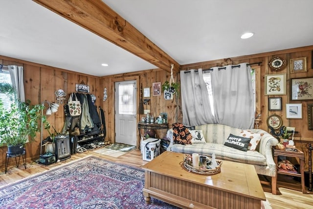 living room featuring wooden walls, beam ceiling, and light wood-type flooring