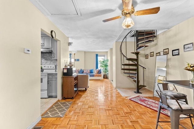 interior space with gray cabinets, white range with electric stovetop, tasteful backsplash, light parquet floors, and ceiling fan