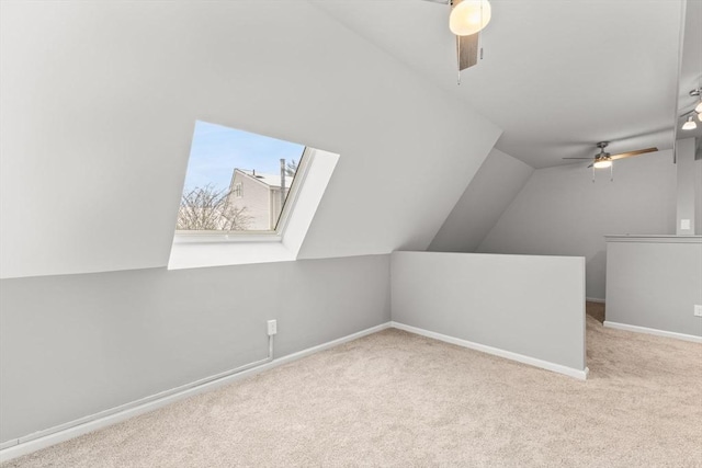 additional living space featuring ceiling fan, lofted ceiling with skylight, and light carpet