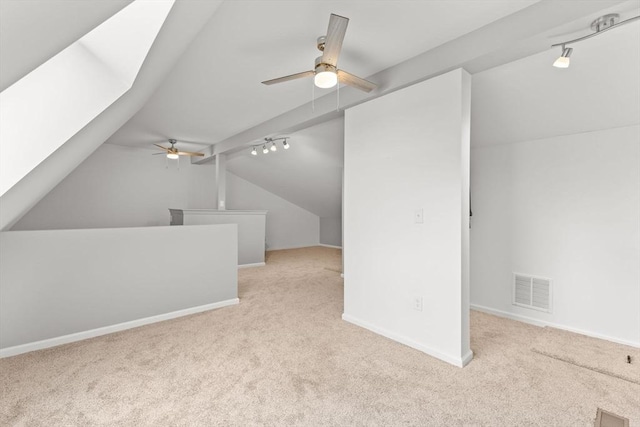 additional living space featuring lofted ceiling with skylight, light colored carpet, and ceiling fan