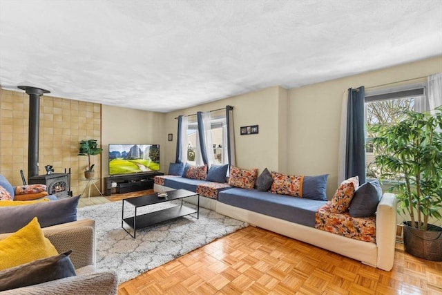 living room featuring a textured ceiling, a wood stove, and light parquet floors