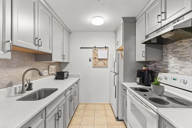 kitchen featuring gray cabinetry, sink, white appliances, and a barn door