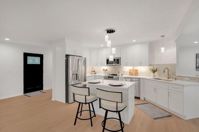 831 Morgan Rd, West Springfield, MA 01089 - kitchen with appliances with stainless steel finishes, light wood-style flooring, tasteful backsplash, white cabinetry, and a breakfast bar