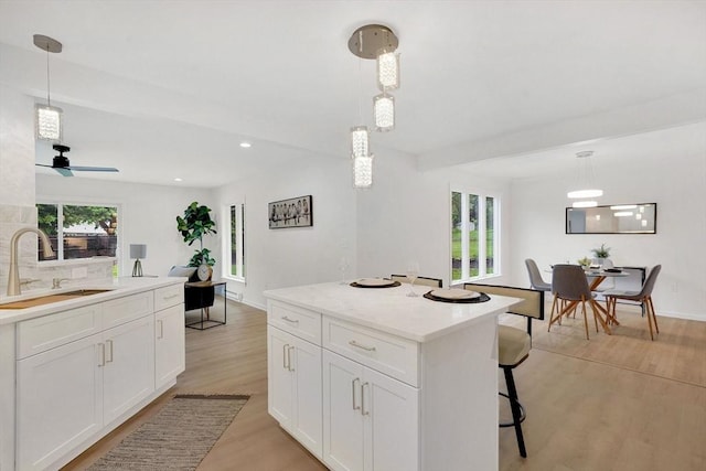 831 Morgan Rd, West Springfield, MA 01089 - kitchen featuring light wood-type flooring, white cabinetry, light countertops, a breakfast bar, and hanging light fixtures