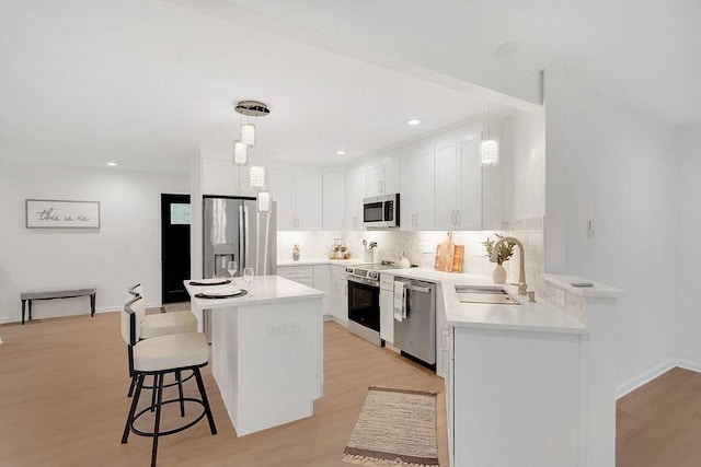 831 Morgan Rd, West Springfield, MA 01089 - kitchen with stainless steel appliances, decorative backsplash, light wood-style flooring, a breakfast bar, and recessed lighting
