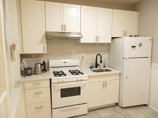 kitchen with white appliances, light tile patterned floors, sink, white cabinets, and tasteful backsplash