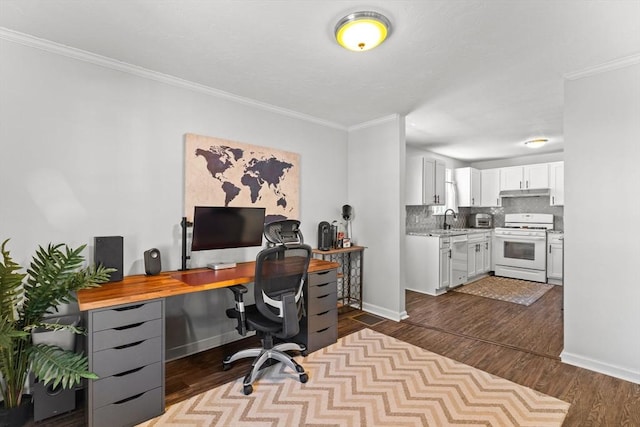 home office with ornamental molding, dark wood-type flooring, baseboards, and a sink