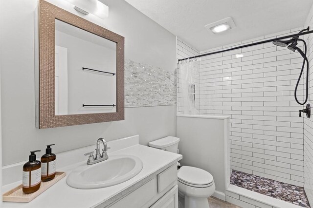 bathroom with vanity, toilet, and a tile shower