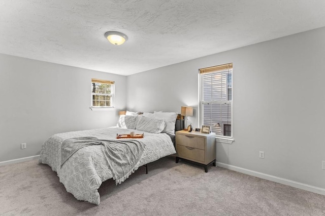 bedroom featuring a textured ceiling, baseboards, and light carpet