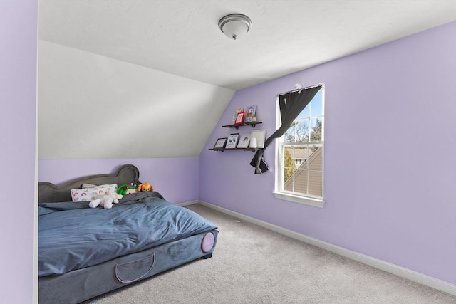 carpeted bedroom with lofted ceiling and baseboards