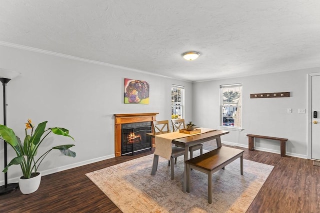 dining area with baseboards, a tiled fireplace, ornamental molding, wood finished floors, and a textured ceiling