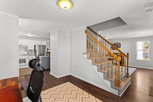 stairs with baseboards, wood finished floors, and ornamental molding