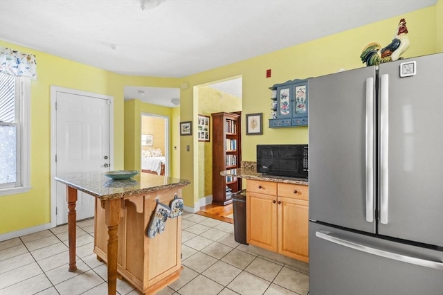 48 Northey St Unit 48, Salem, MA 01970 - kitchen featuring freestanding refrigerator, black microwave, a kitchen island, light tile patterned floors, and stone countertops