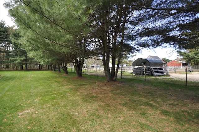 view of yard with fence, a carport, and an outdoor structure