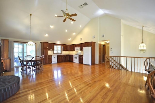 living area with visible vents, light wood finished floors, ceiling fan with notable chandelier, and high vaulted ceiling