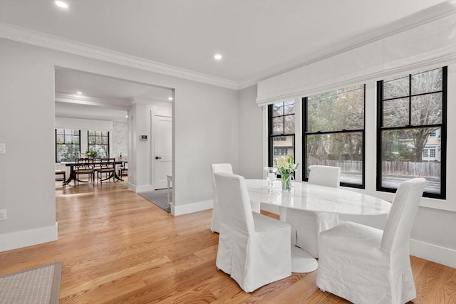 dining area with baseboards, ornamental molding, and light wood finished floors