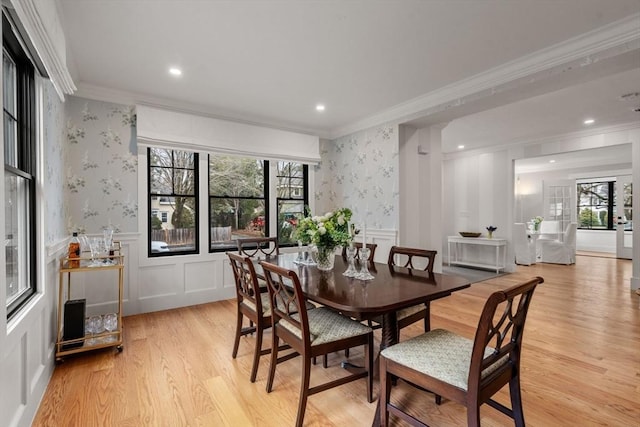 dining space with wallpapered walls, plenty of natural light, a wainscoted wall, and ornamental molding