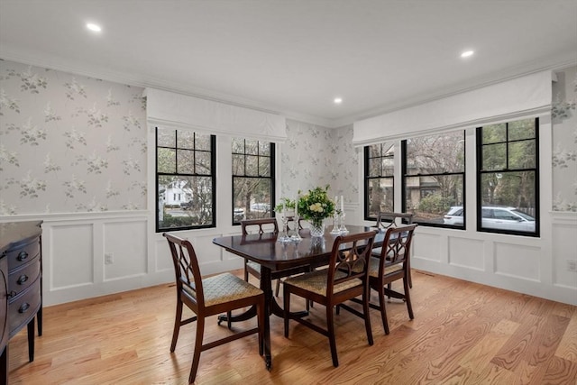 dining room featuring a wealth of natural light, light wood finished floors, crown molding, and wallpapered walls