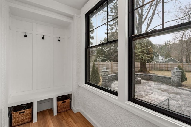 mudroom with a textured wall, light wood-type flooring, and baseboards