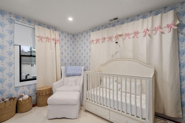 bedroom with visible vents, a crib, wallpapered walls, and carpet floors