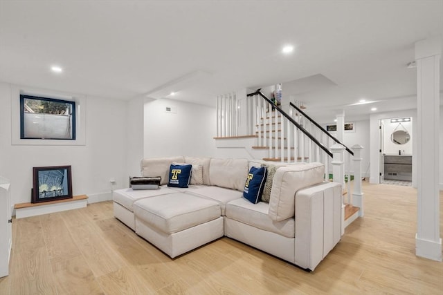 living area featuring stairs, recessed lighting, a fireplace with raised hearth, and light wood-type flooring