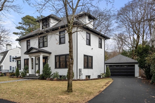 american foursquare style home with a garage, stucco siding, a front lawn, and an outdoor structure