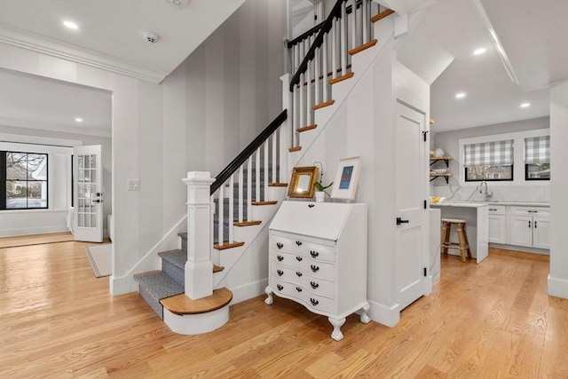 staircase featuring recessed lighting, ornamental molding, baseboards, and wood finished floors