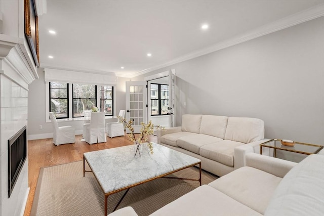 living room featuring recessed lighting, light wood-style floors, a fireplace, crown molding, and baseboards