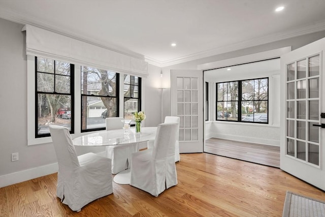 dining space featuring a healthy amount of sunlight, light wood-style floors, baseboards, and ornamental molding