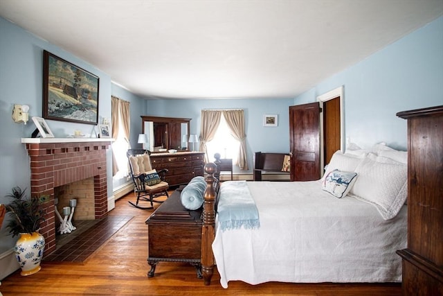 bedroom with hardwood / wood-style flooring and a brick fireplace