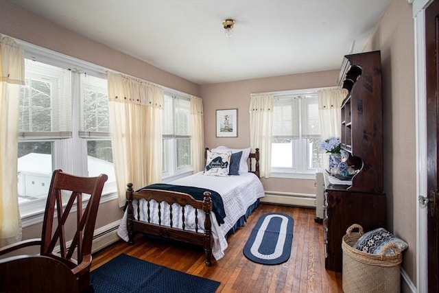 bedroom featuring a baseboard heating unit and dark hardwood / wood-style floors