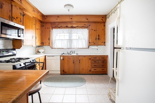 kitchen featuring sink, white appliances, light tile patterned floors, and backsplash