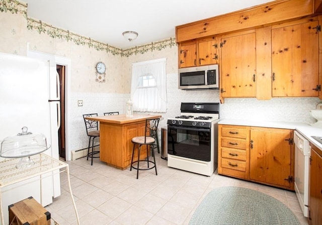 kitchen featuring dishwasher, baseboard heating, a kitchen breakfast bar, a kitchen island, and gas range