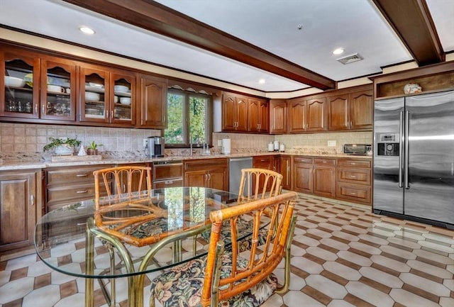 kitchen with light stone countertops, appliances with stainless steel finishes, and tasteful backsplash