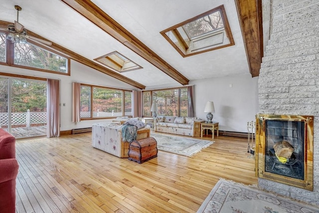 living room with a skylight, ceiling fan, light wood-type flooring, a baseboard radiator, and beam ceiling