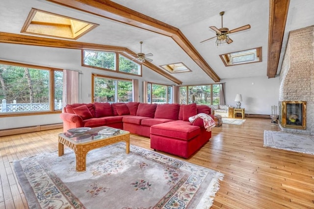 living room with a wealth of natural light, vaulted ceiling with skylight, ceiling fan, and light wood-type flooring