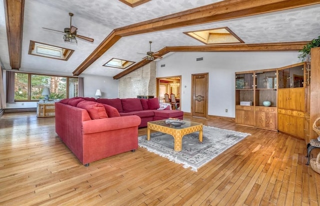 living room featuring beamed ceiling, a skylight, and light hardwood / wood-style flooring