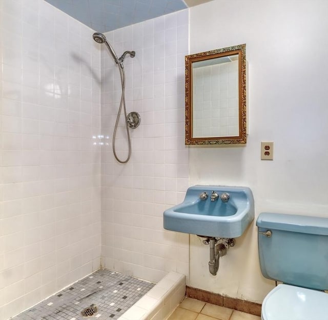 bathroom with tiled shower, tile patterned flooring, toilet, and sink